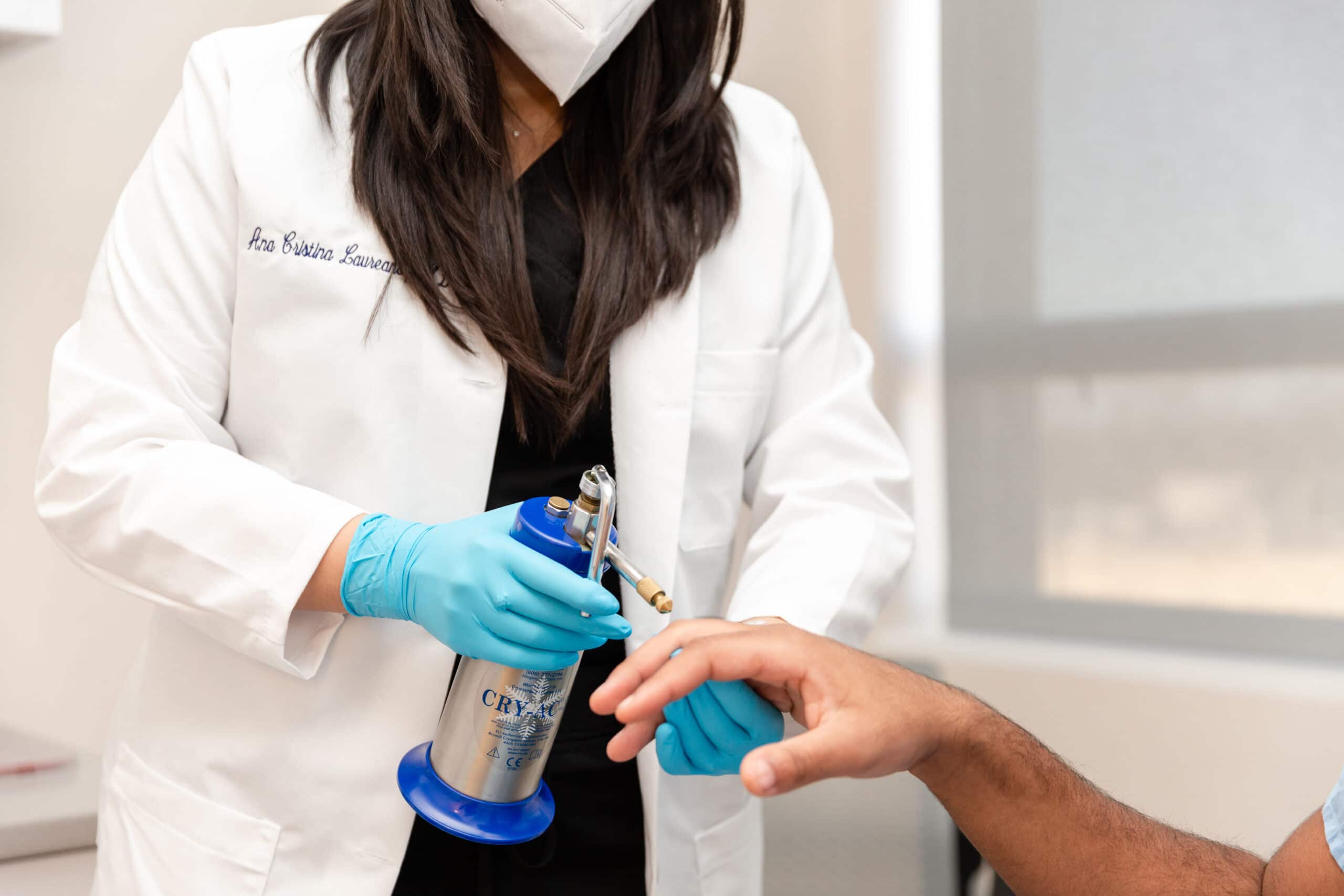 doctor treating skin growths on the patient's hands