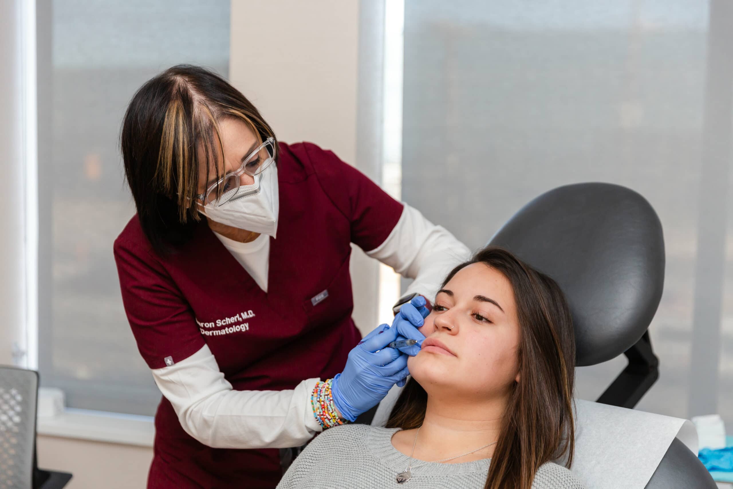 doctor performing a radiesse injecton on a female patient